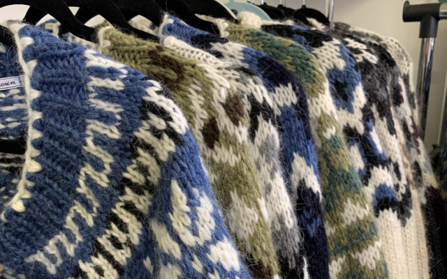 Una serie di maglioni islandesi appesi con le stampelle, caratterizzati dalle decorazioni colorate sul collo